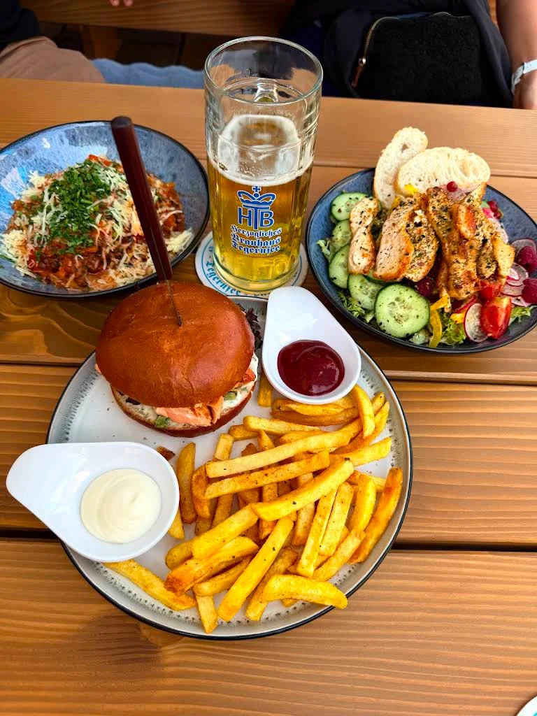 Burger mit Pommes, frischer Salat und Pasta auf dem Tisch bei Laura’s Stüberl
